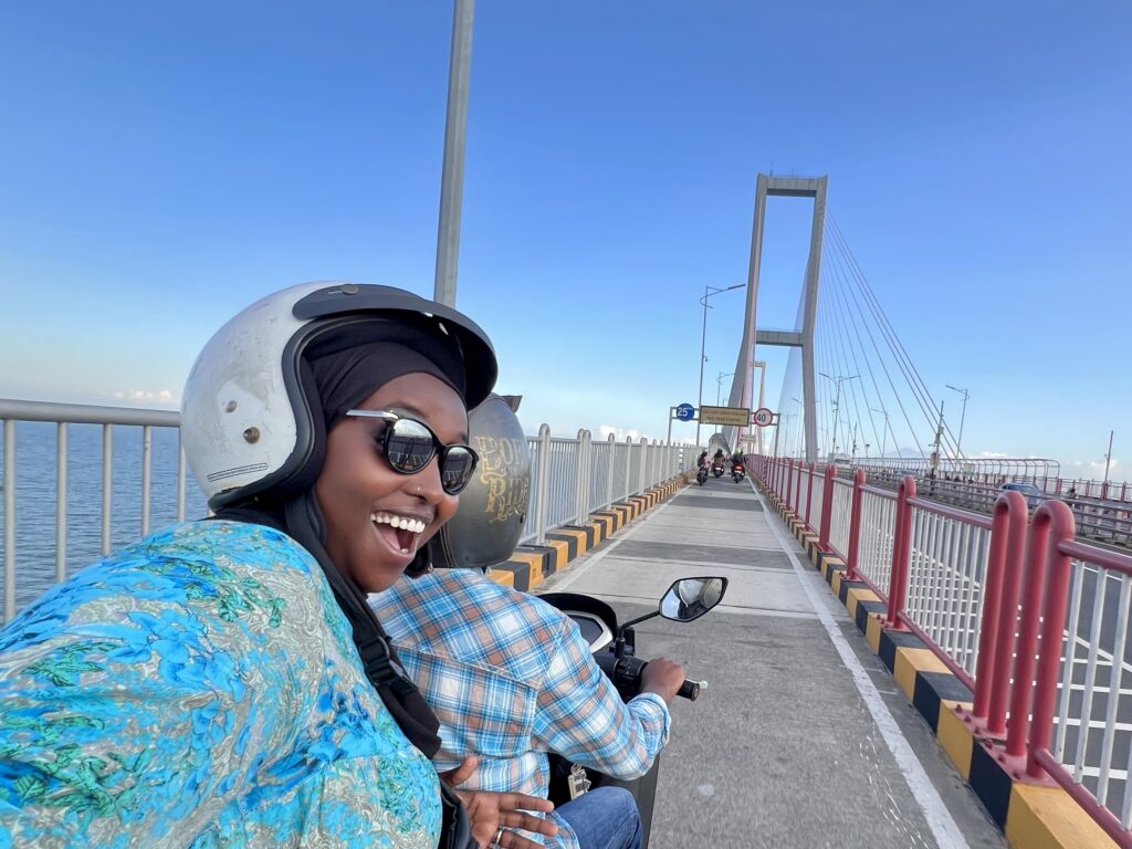 Marian, travel storyteller behind Marian on the Move, riding a motorbike on the Suramadu Bridge in Surabaya, Indonesia